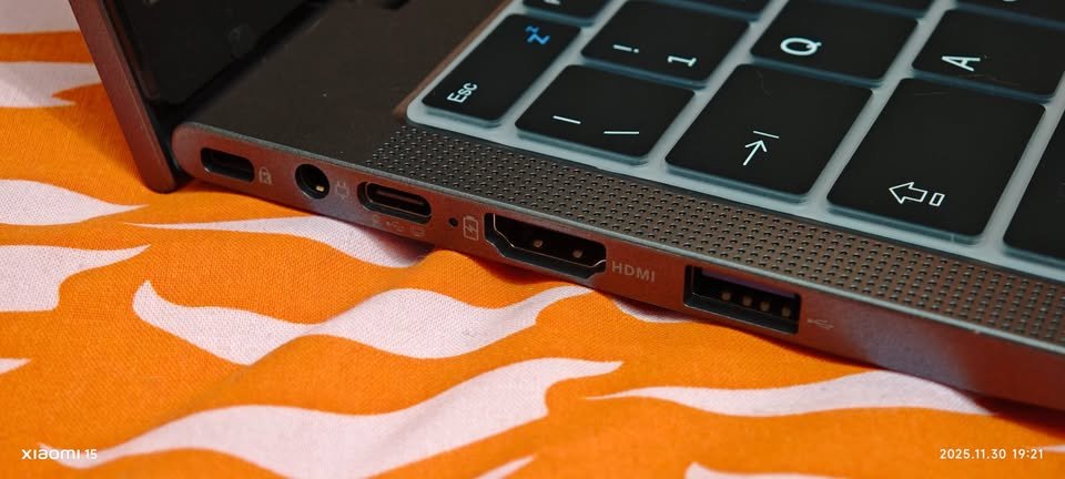 Close-up side view of laptop chassis connectivity ports including a USB-C port, a dedicated DC power input jack, an HDMI output, and a standard USB-A port next to the keyboard assembly.